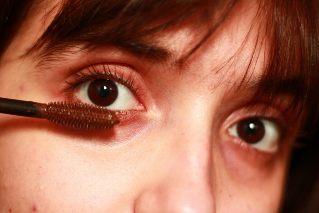 A woman is putting mascara on her eye