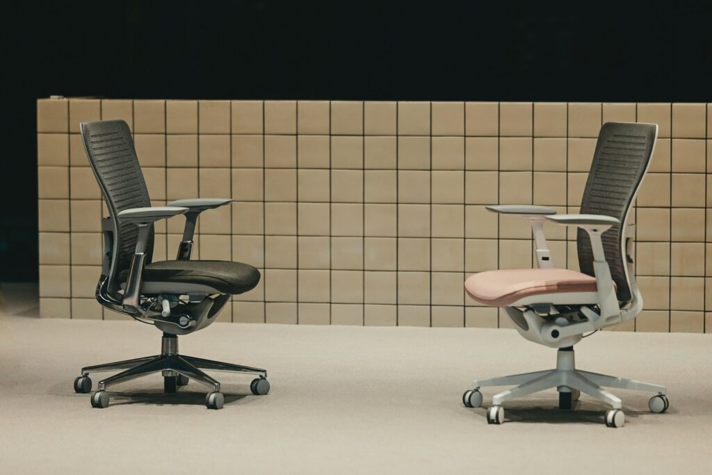 Two ergonomic office chairs, dark and light, facing each other.
