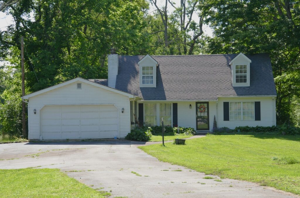 A white house with a garage, driveway, and green lawn.