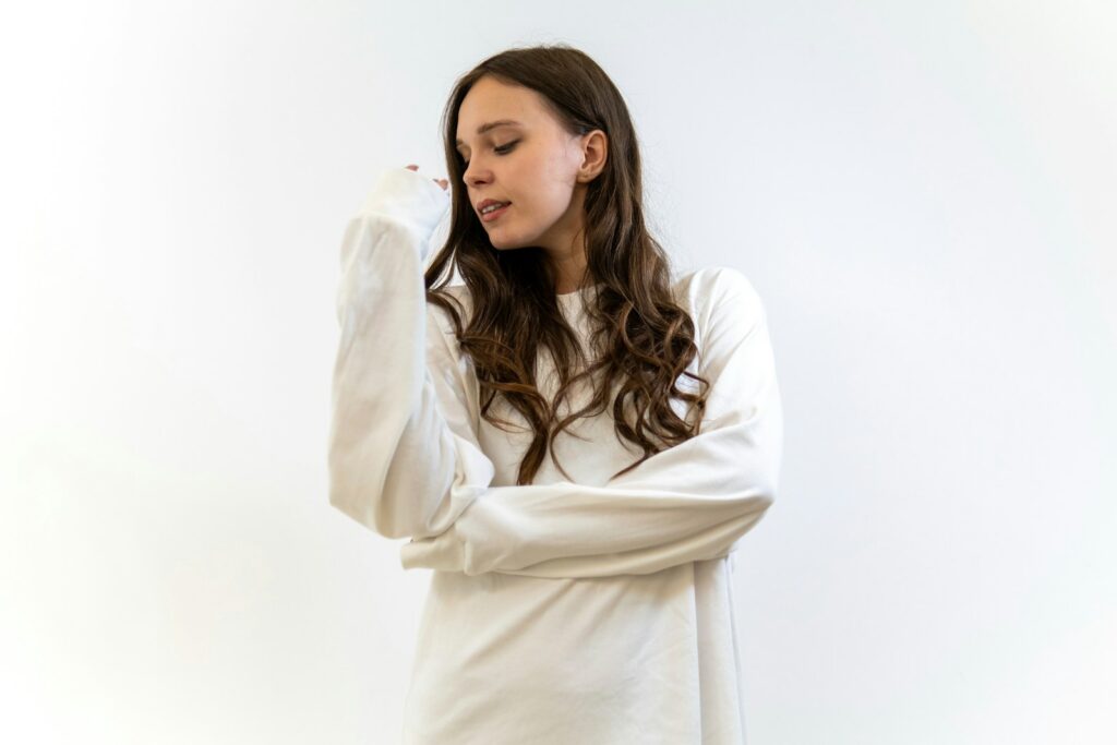 A young woman in a white straitjacket looking down.