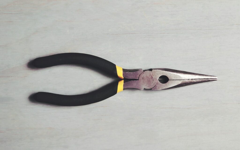 A pair of black and yellow pliers on a white surface