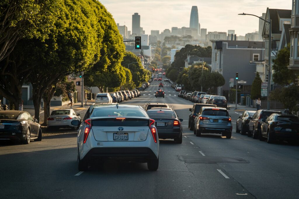 Cars drive down a city street toward the skyline.