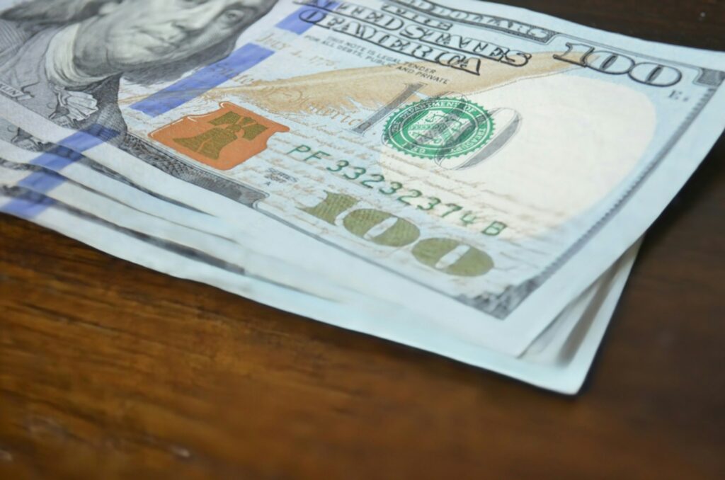 Here's a short caption: hundred dollar bills stacked on a table.