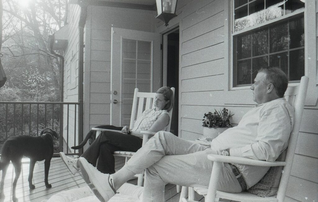 A couple and their dog relaxing on a porch.