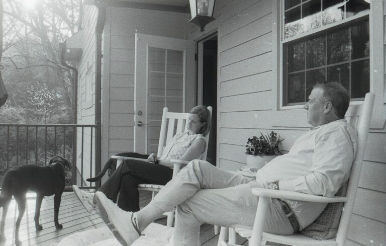 A couple and their dog relaxing on a porch.