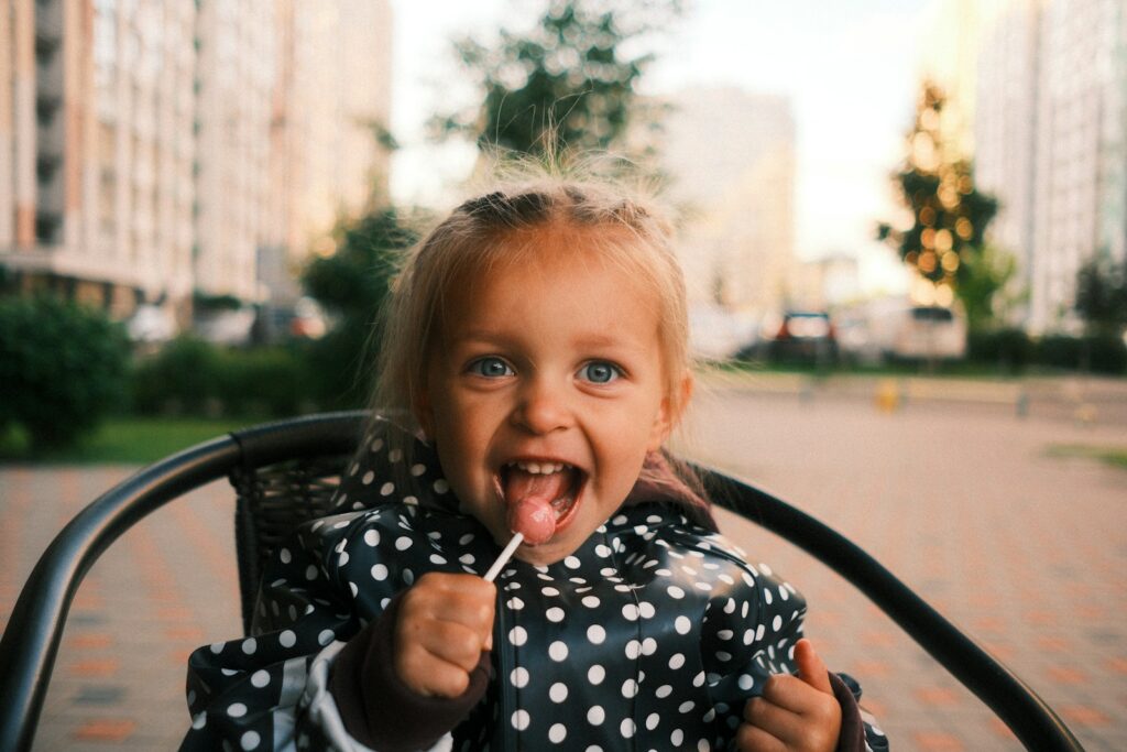 Cheerful girl in polka dots enjoying a lollipop outside.