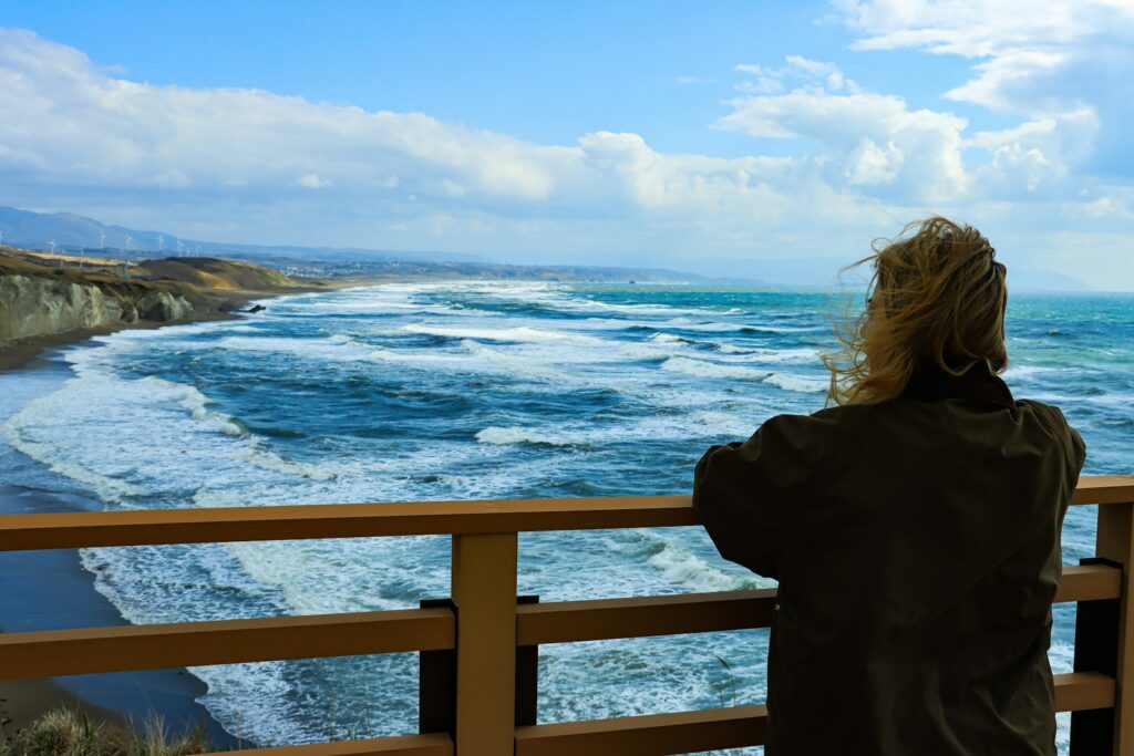 Woman looking at the ocean from a wooden balcony.