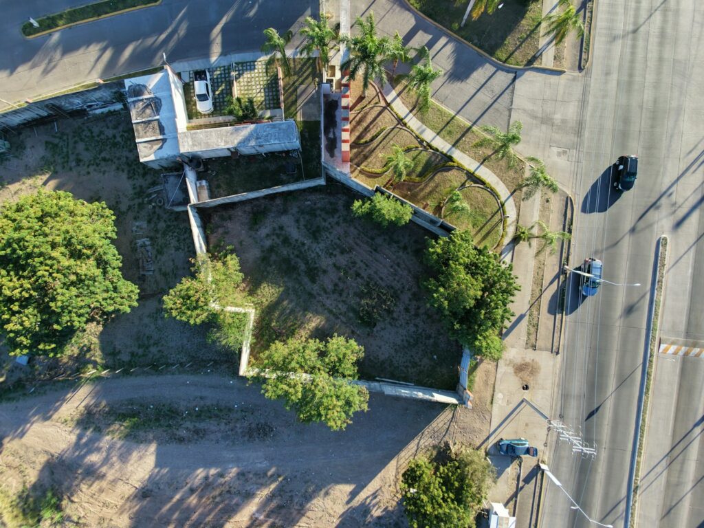 Aerial view of a vacant lot with trees and street.
