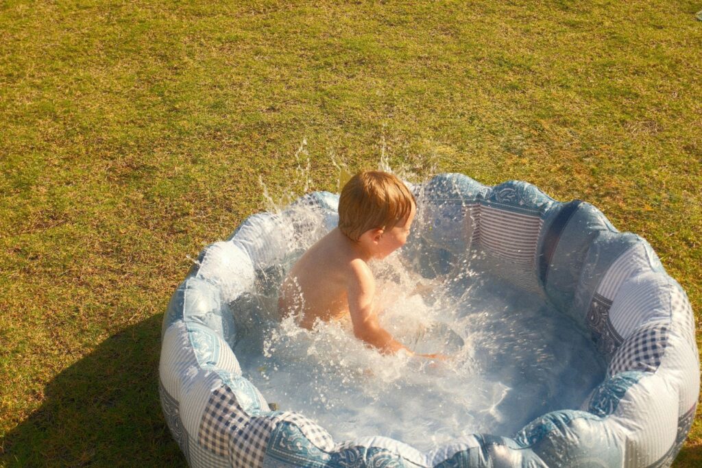 A child splashes in a small inflatable pool.