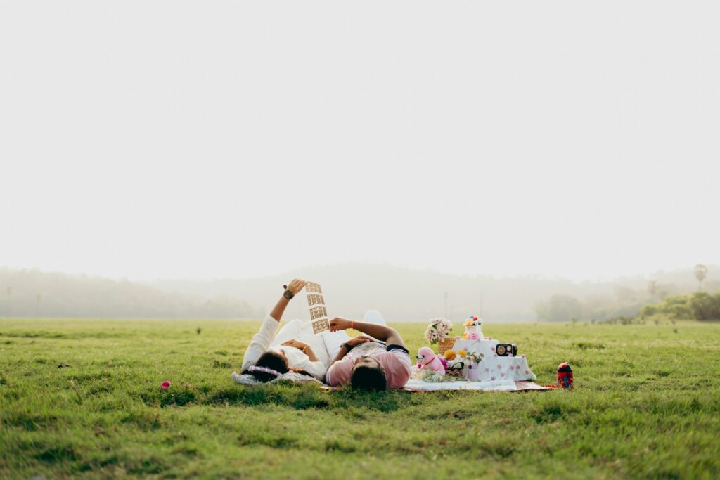 Couple relaxing on a picnic blanket in a grassy field.