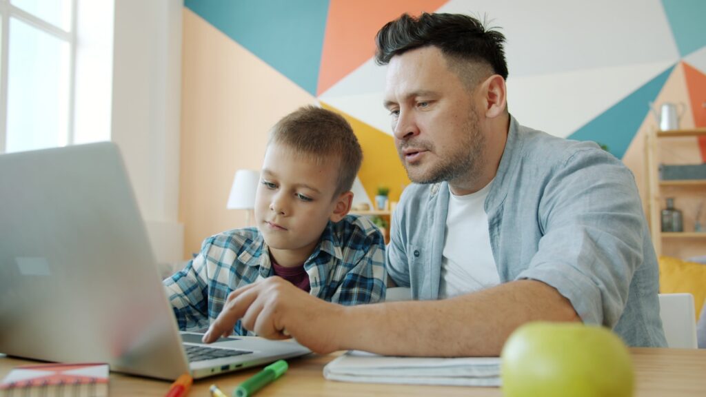 Father and son learning together on a laptop.