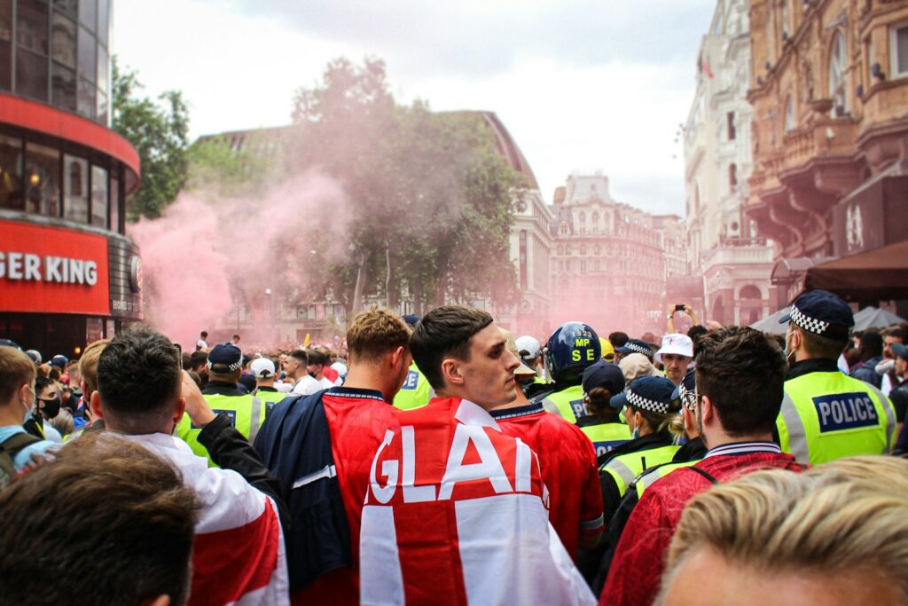 people in red and white jersey shirt standing on street during daytime