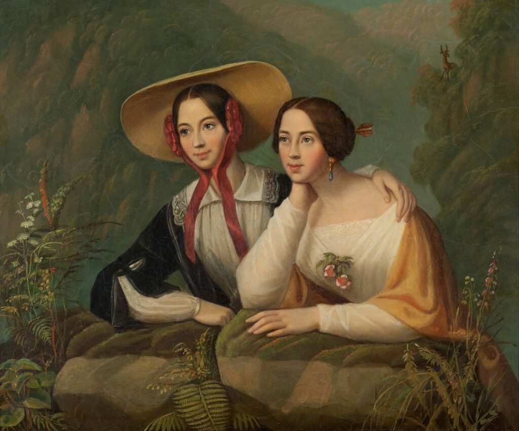 Two women in vintage clothing in a natural setting.