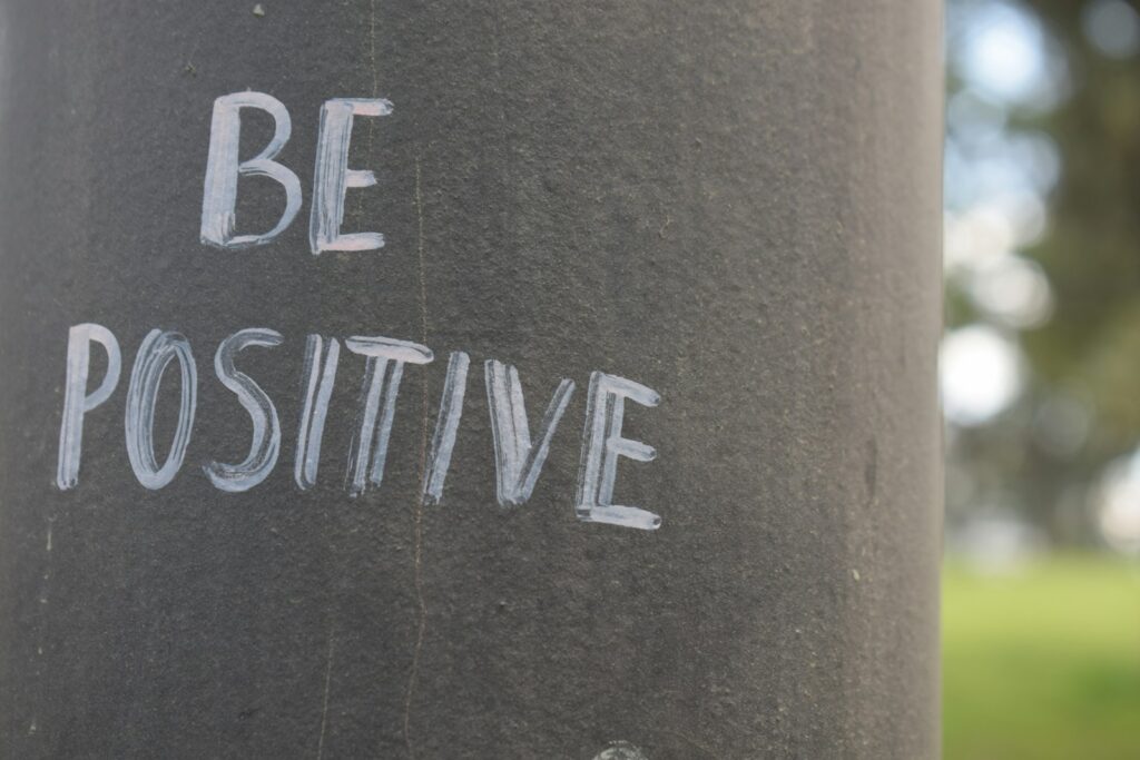 Be positive written on a dark pole.