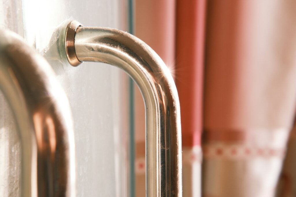 Close-up of a shiny metal door handle with curtains