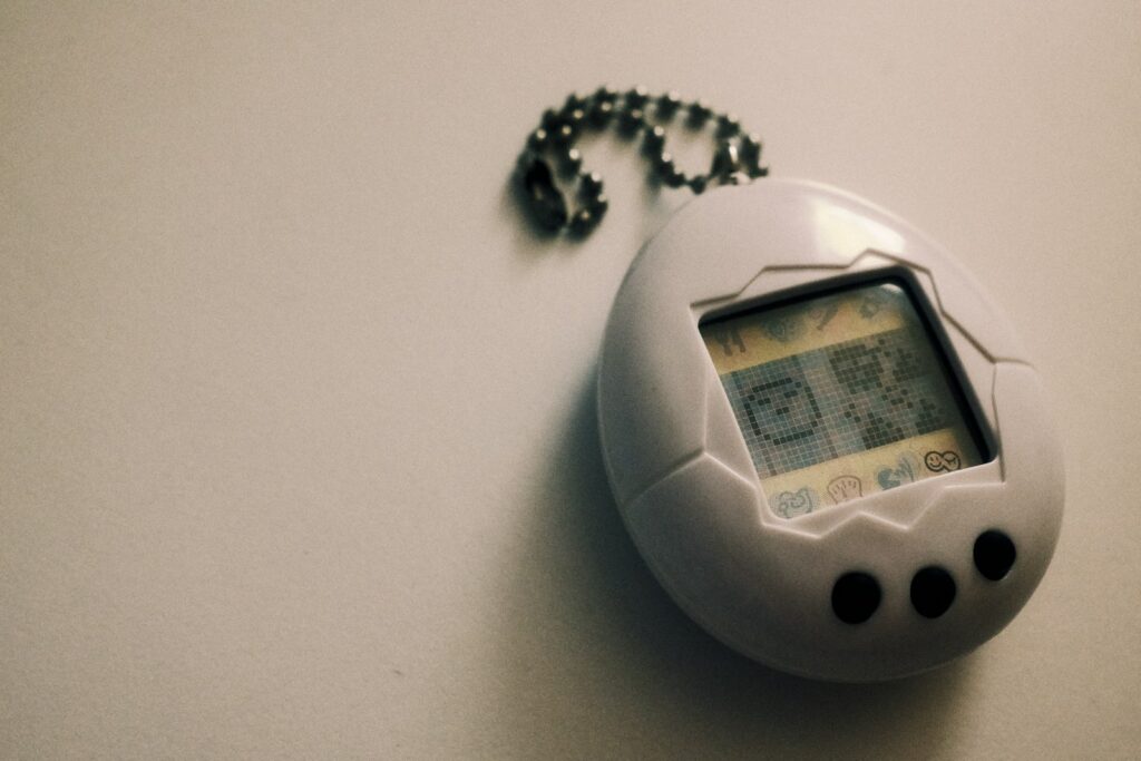 a small Tamagotchi electronic device with a chain attached to it