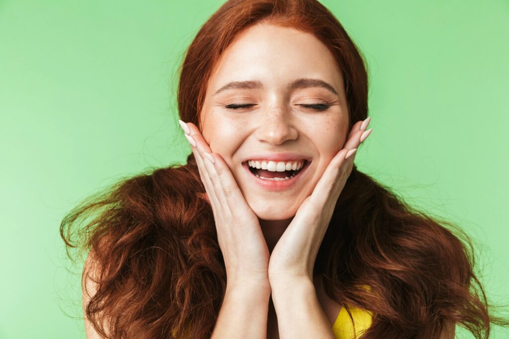 a woman smiling with her hands on her face