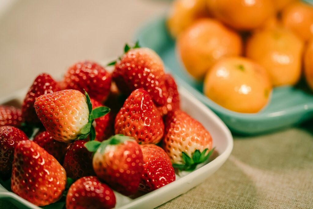 strawberry and orange fruits in bowl as source of Vitamin C