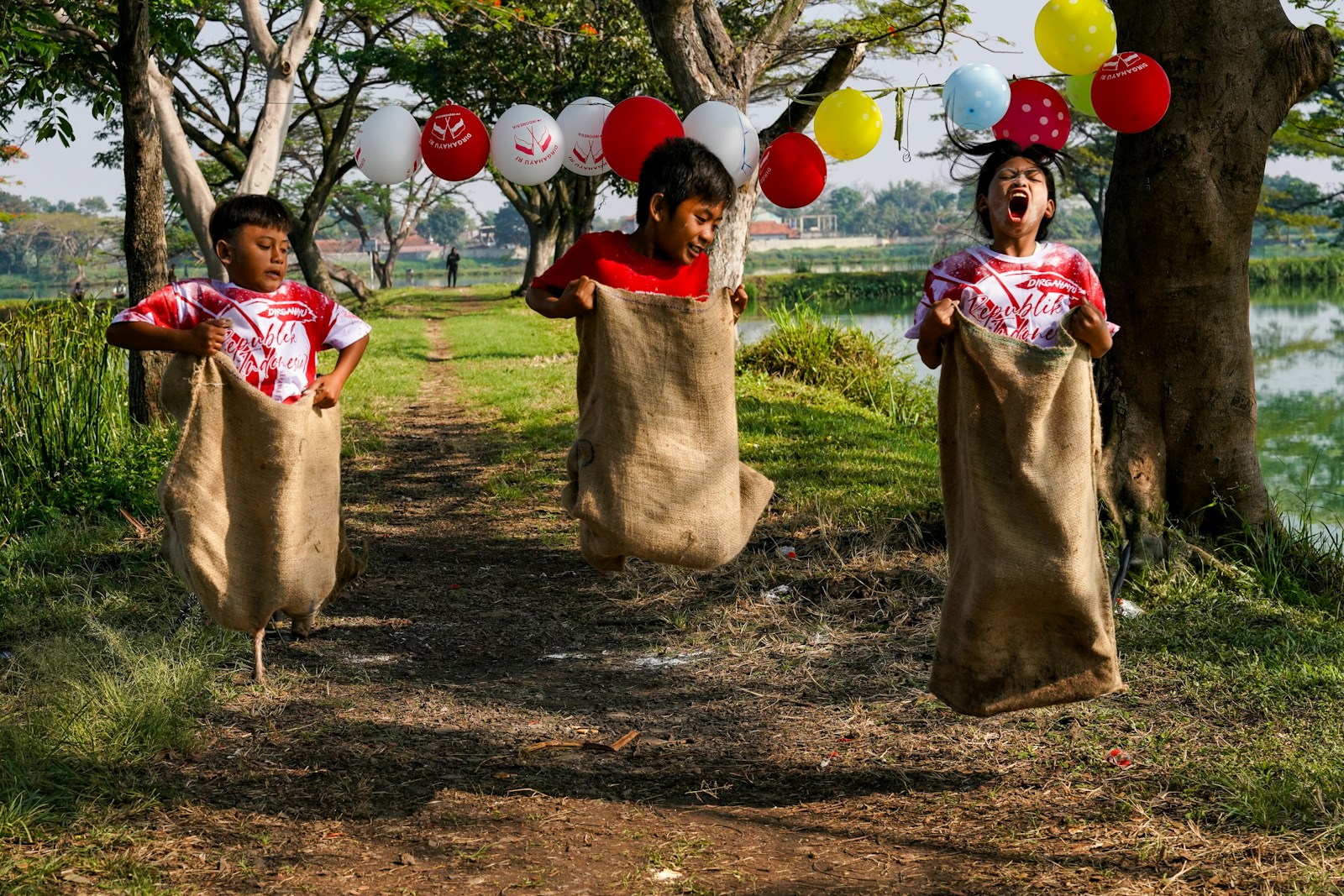 Three children jumping in burlap sacks during a race.