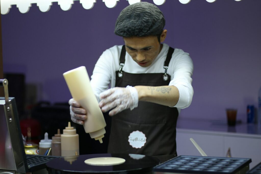 a man in an apron is making a doughnut