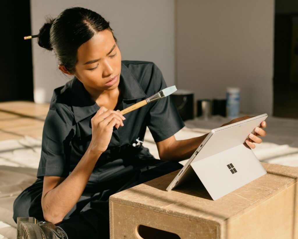a woman sitting on a box holding a paintbrush