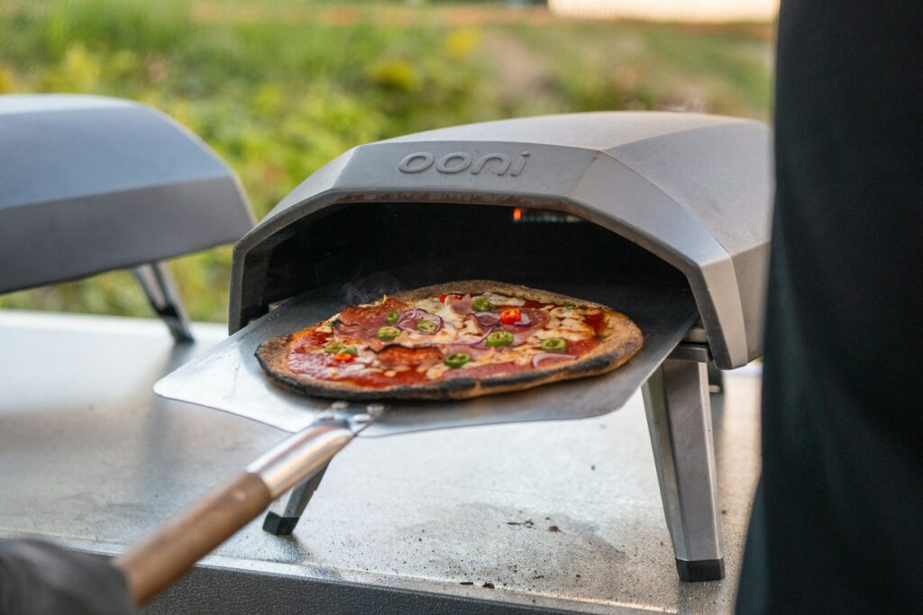 Cooking a homemade pizza in a portable outdoor pizza oven.