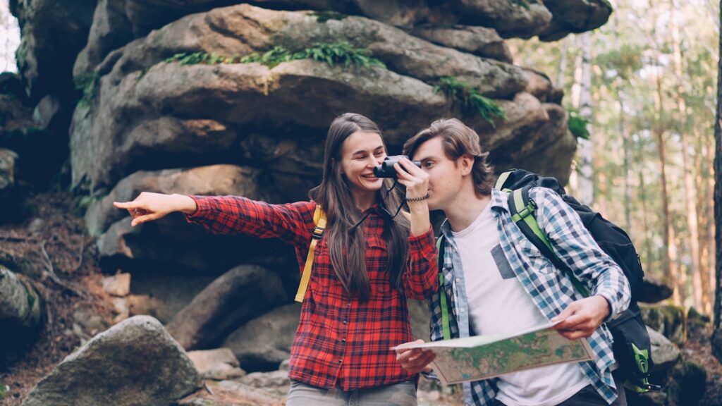 Couple hiking with map and binoculars in forest