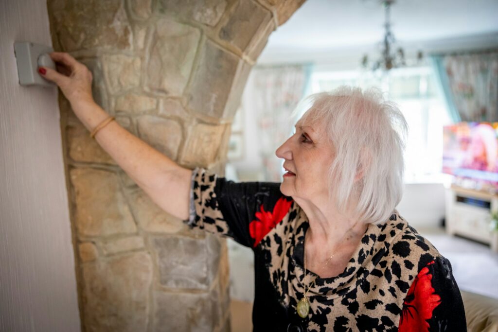 an older woman is holding a light switch