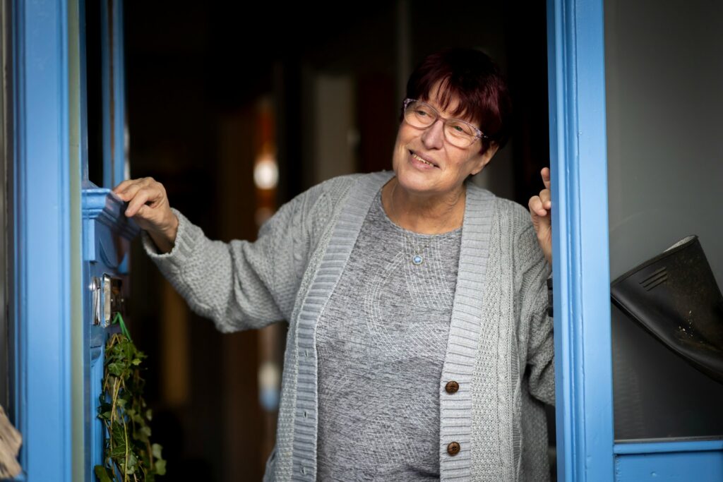 a woman is opening a blue door and smiling