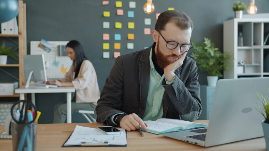 Man working at desk with laptop and notebook.