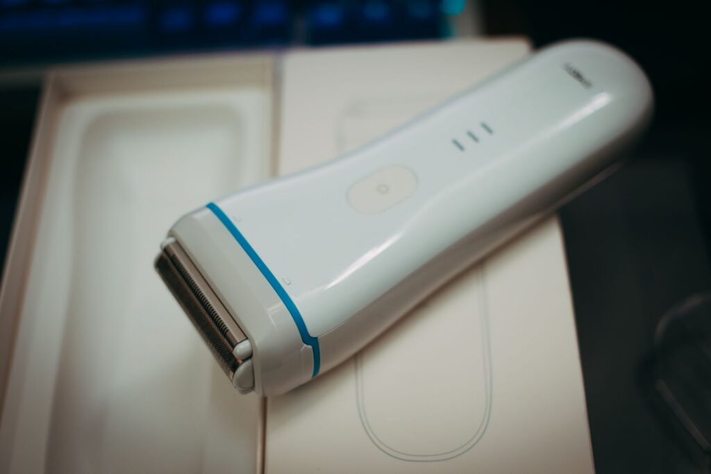 White handheld electric shaver placed on its packaging, showcasing its sleek design and functionality.