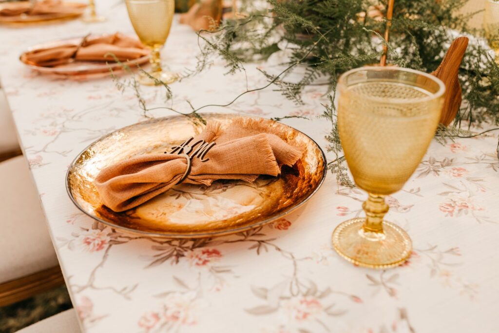 Stylish table setting featuring gold plates, glassware, and floral elements for an elegant dinner.