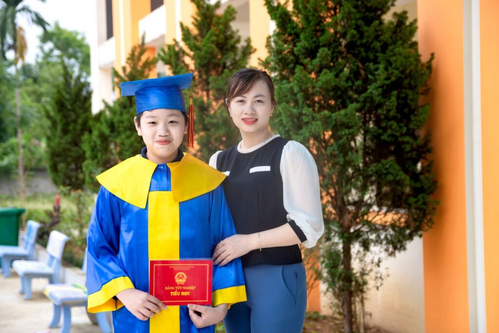 Mother and child celebrate graduation with cap and diploma outdoors.