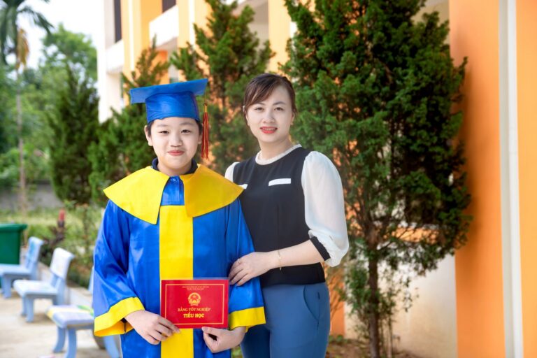 Mother and child celebrate graduation with cap and diploma outdoors.