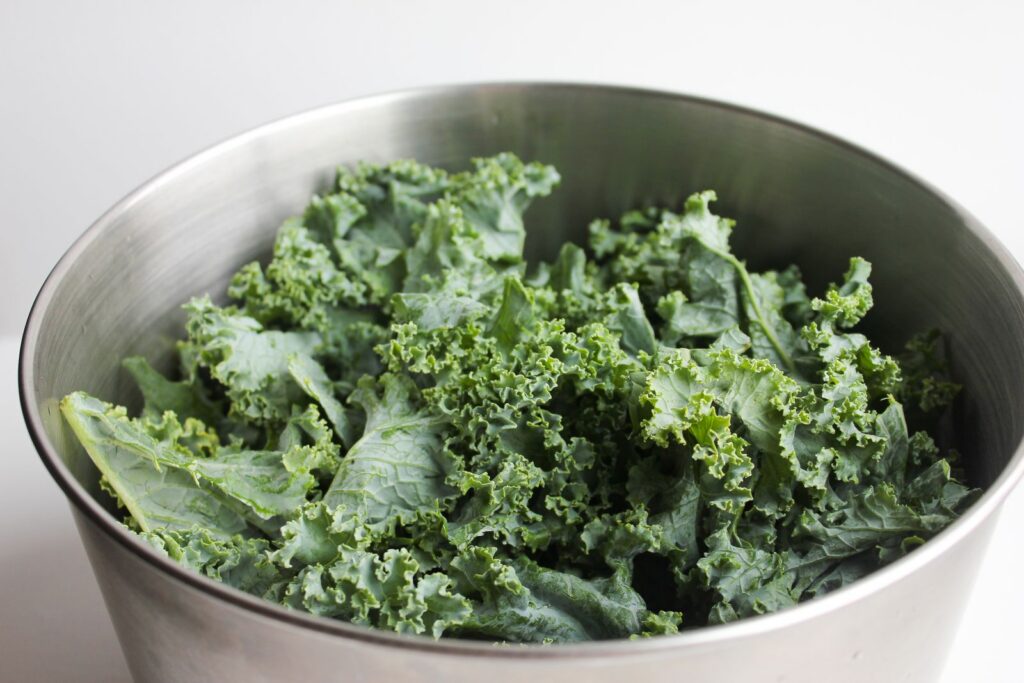 Healthy fresh kale leaves in a stainless steel bowl, perfect for salads and healthy meals.