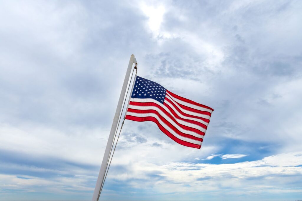 A vibrant American flag waving under a scenic cloudy sky, symbolizing patriotism and national pride.