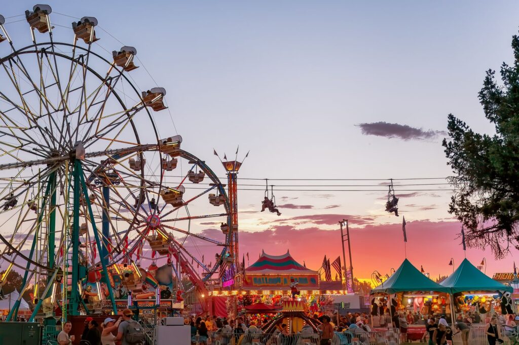 A lively amusement park scene with rides and crowds during a colorful sunset.