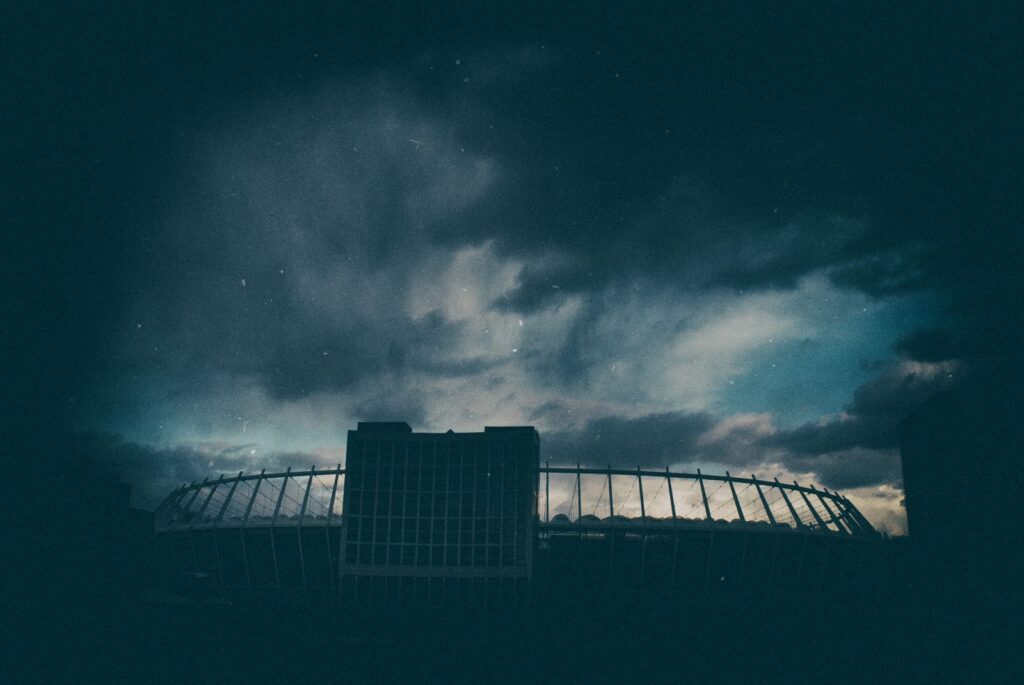 Dark and moody night sky with a stadium silhouette in Kyiv, creating an atmospheric scene.