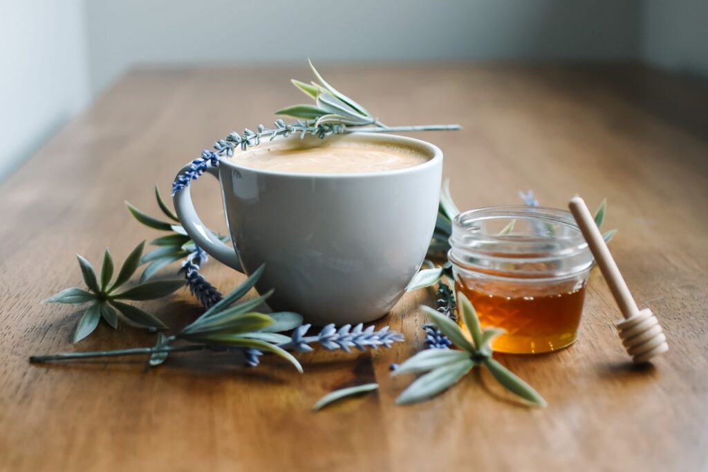 Serene still life of a coffee cup, jar of honey, and lavender flowers on a wooden table.