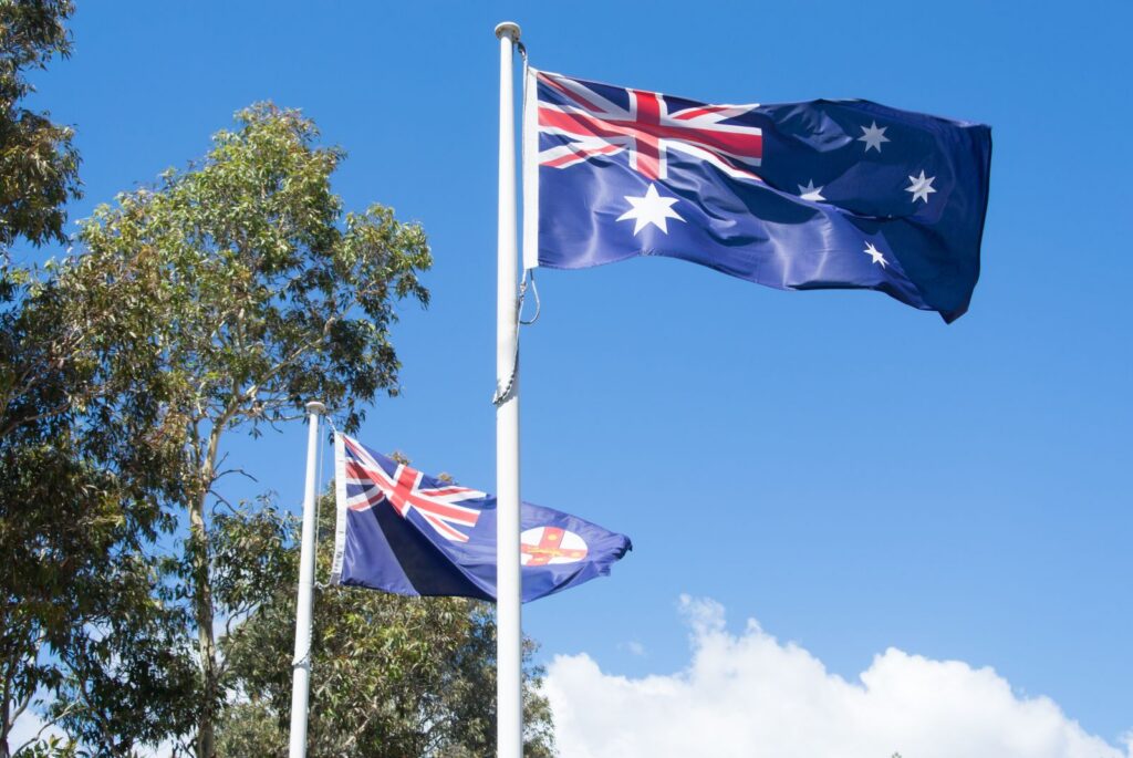 Flying Australian flags with blue sky in Sydney, symbolizing patriotism and national pride.