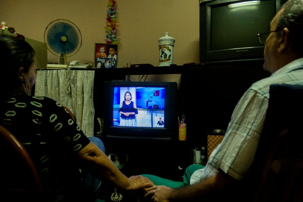 a man and a woman sitting in front of a tv