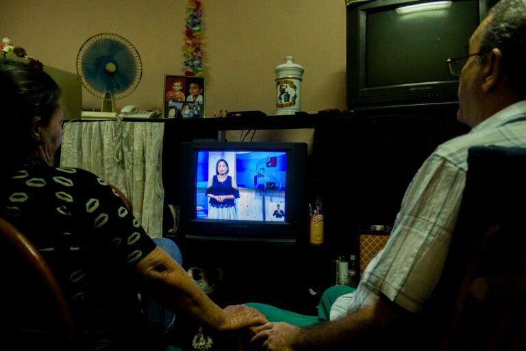 a man and a woman sitting in front of a tv
