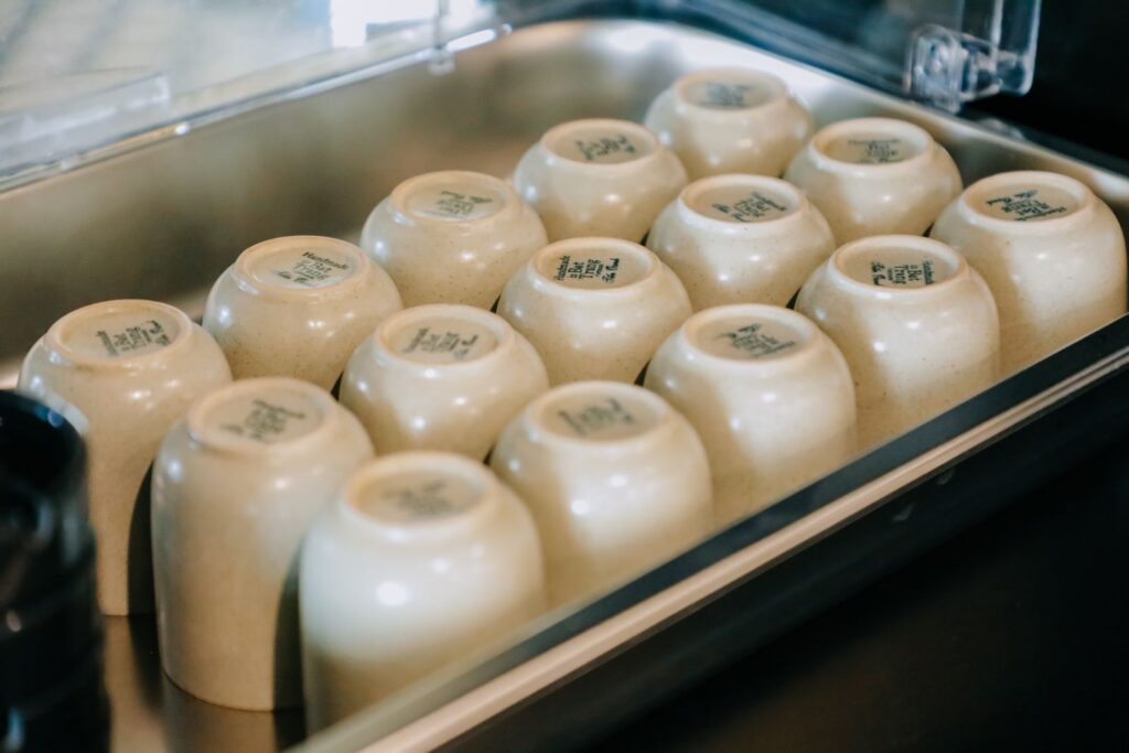 Close-up view of upside-down ceramic cups arranged neatly on a metal tray in a well-lit setting.