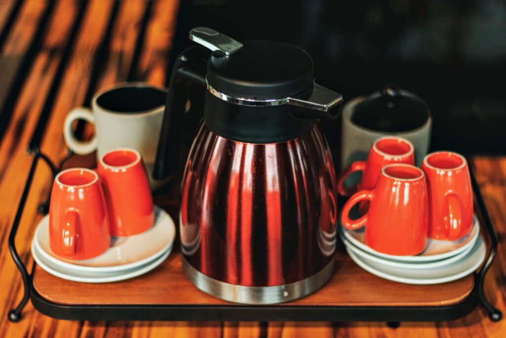 Close-up of a stylish coffee set with red cups and kettle on a wooden tray, perfect for morning routines.