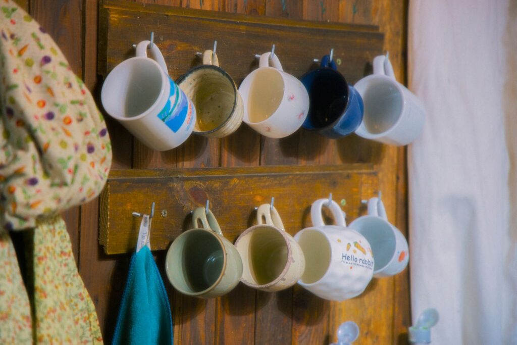 Rustic wooden rack with ceramic mugs hanging neatly, evoking cozy kitchen vibes.