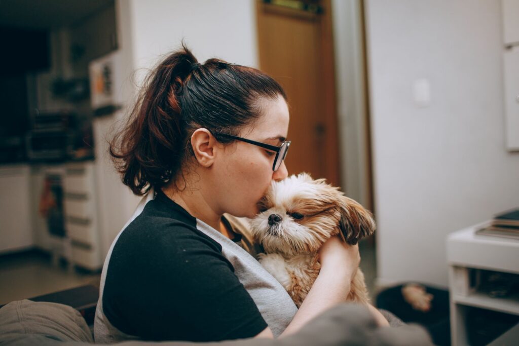 A woman lovingly holds her Shih Tzu dog in a warm indoor environment.