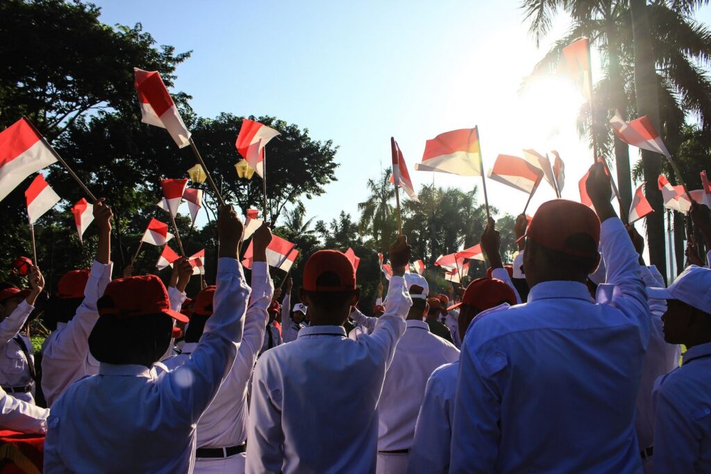 Crowd celebrating with Indonesian flags outdoors in Jakarta.