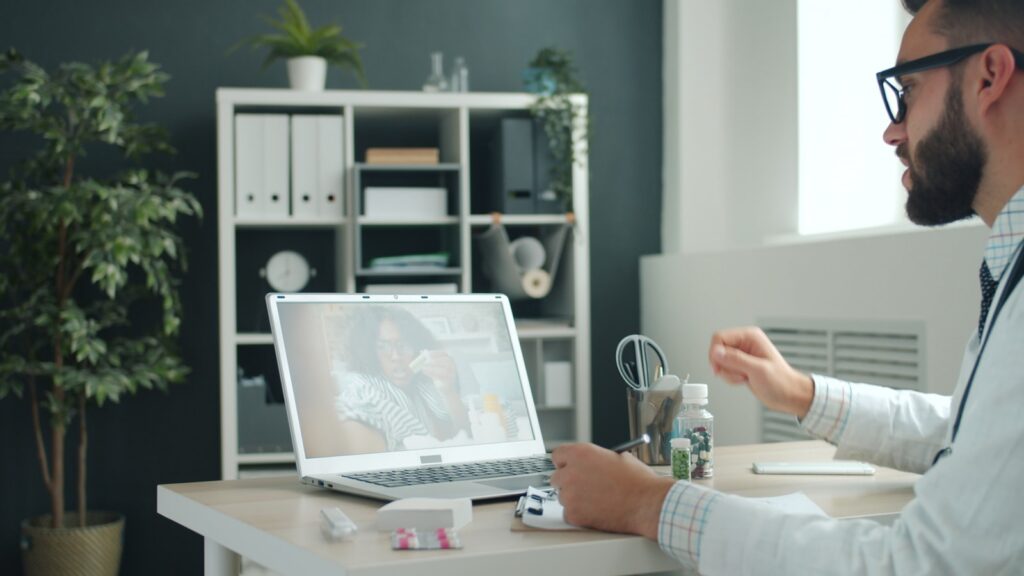 Doctor consulting patient online via laptop computer.