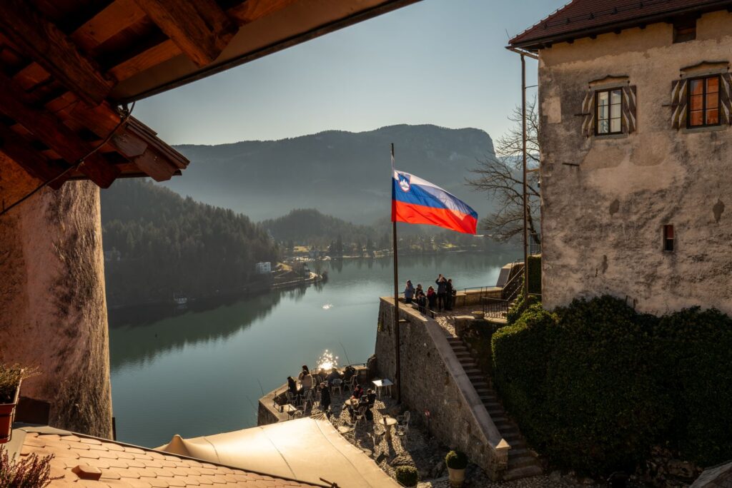 A picturesque view of Lake Bled from Bled Castle, featuring the Slovenian flag.