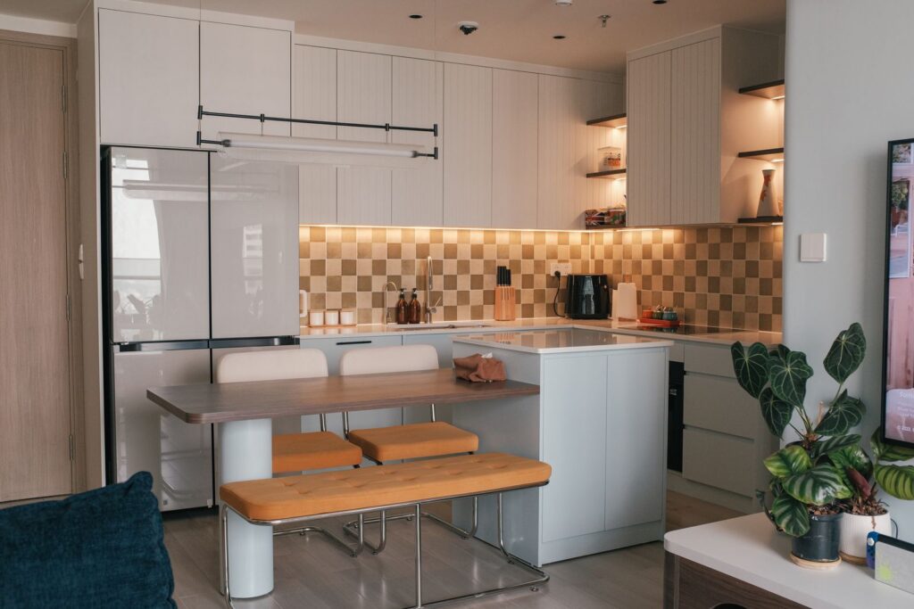 Stylish modern kitchen interior with bench seating, seamless cabinets, and warm lighting.